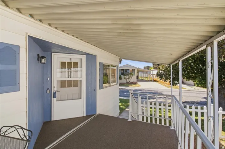 Covered porch with metal railing, privacy screens, and exterior wall lighting