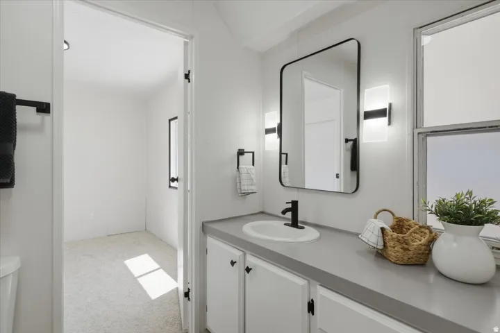 Bathroom vanity featuring a single basin sink, matte black faucet, and a large wall-mounted mirror