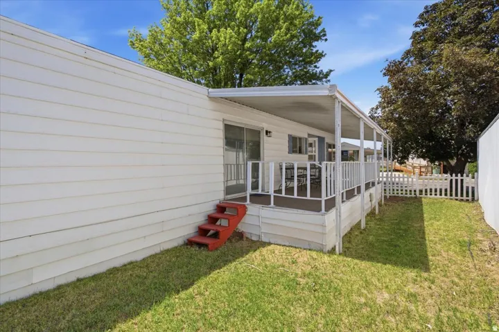 Covered porch with white railing, sliding glass door entry, and white picket fencing