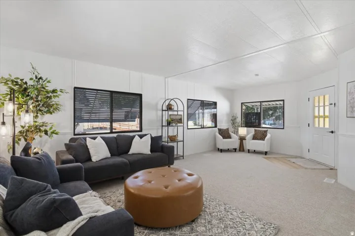 Recessed lighting, light-toned carpeting, paneling on walls, white interior door with glass panes, and black-framed windows