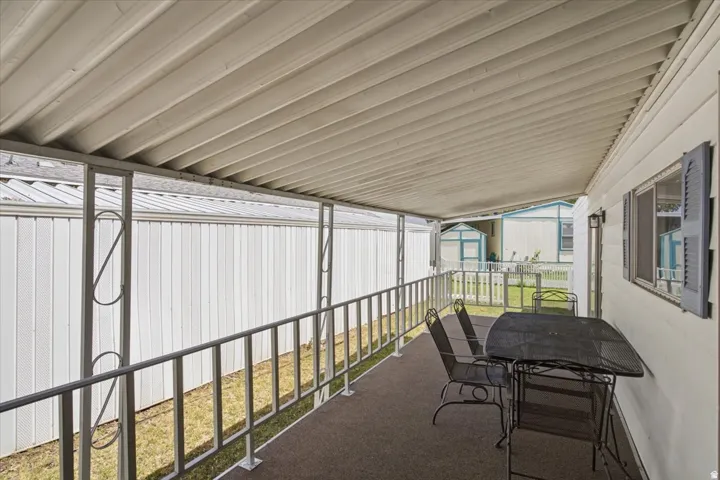 Covered patio with metal railing and exterior wall sconce