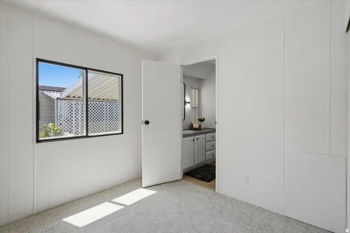 White paneled wall finishes, light carpeting, and a black-framed window
