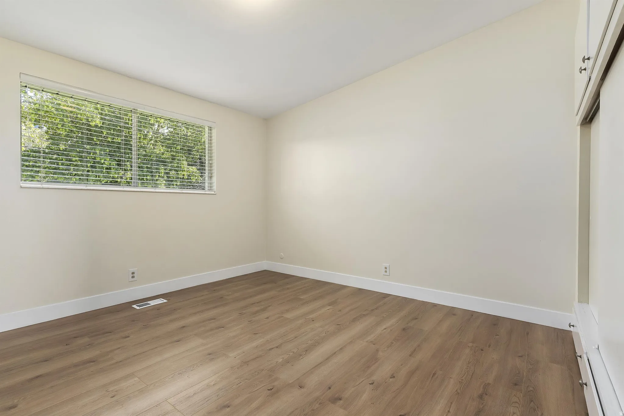 Recessed ceiling lighting, wood-finish flooring, and a window with blinds