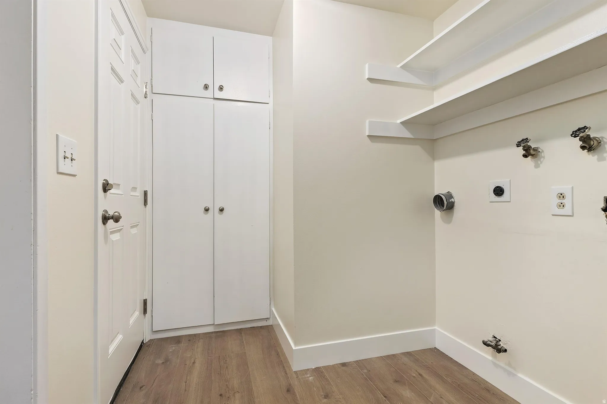 Integrated cabinetry with upper and lower storage, wood-finish flooring, and wall-mounted shelving