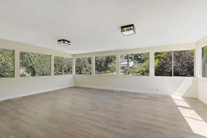 Expansive room featuring wood-finish flooring, numerous large windows, and two flush-mount ceiling lights
