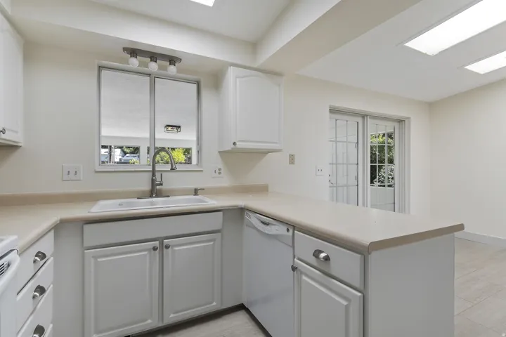 Kitchen featuring white cabinetry, light-toned countertops, an undermount sink, and a built-in dishwasher