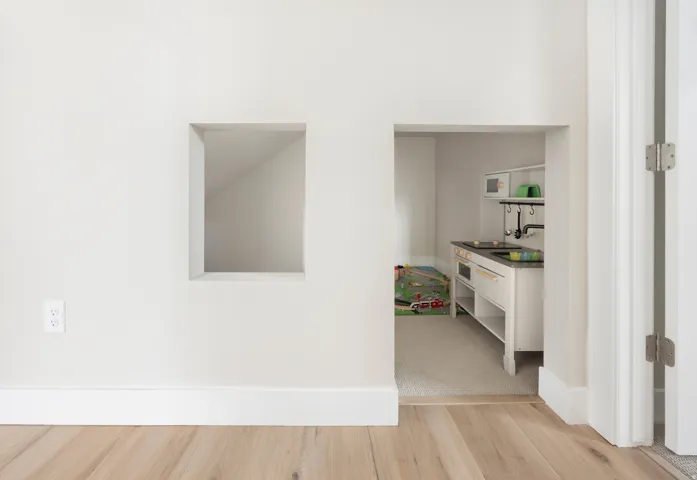 Light wood-finish flooring with white baseboards and wall trim