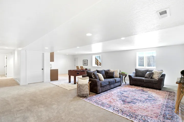 Expansive carpeted living area with recessed lighting, white walls, and built-in cabinetry