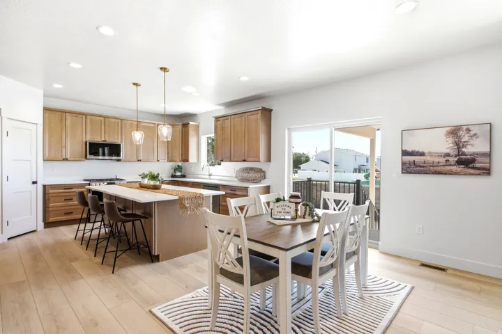 Open-concept kitchen and dining area featuring wood-finish flooring, recessed lighting, and a kitchen island with seating