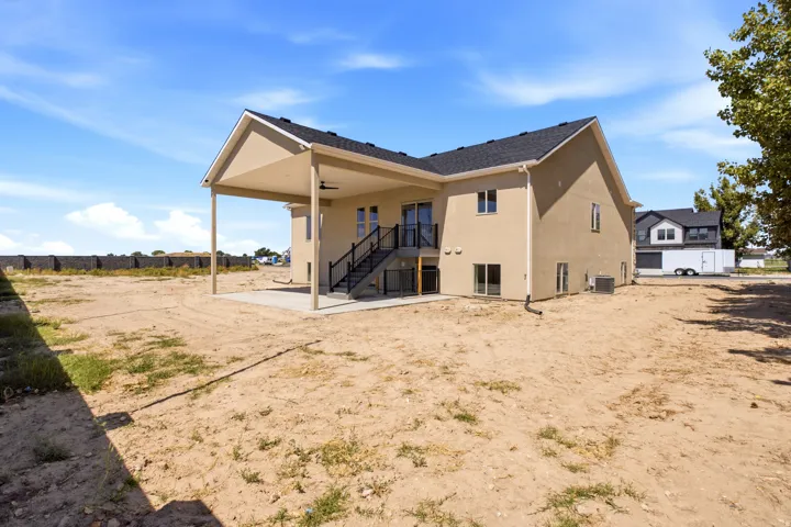 Rear exterior with a covered patio, concrete slab, and black metal railing