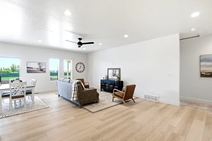 Recessed ceiling lighting, wood-finish flooring, multiple windows, and a ceiling fan with integrated lighting