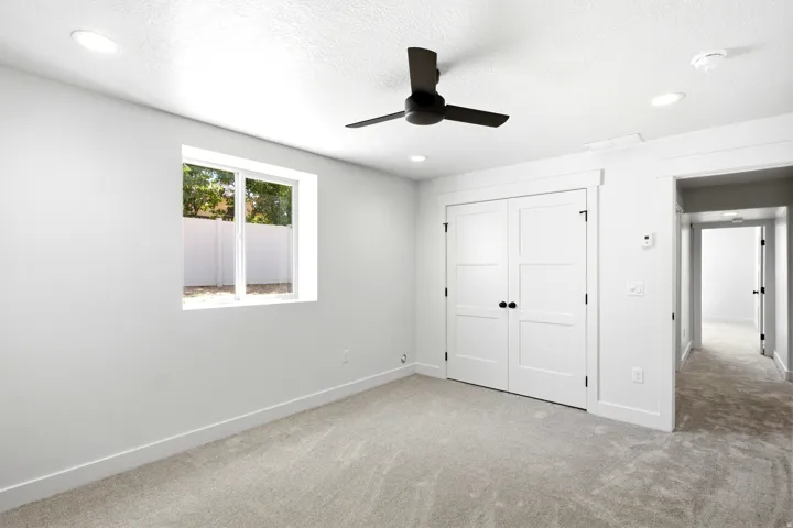 Plush carpeting, recessed lighting, and a modern ceiling fan
