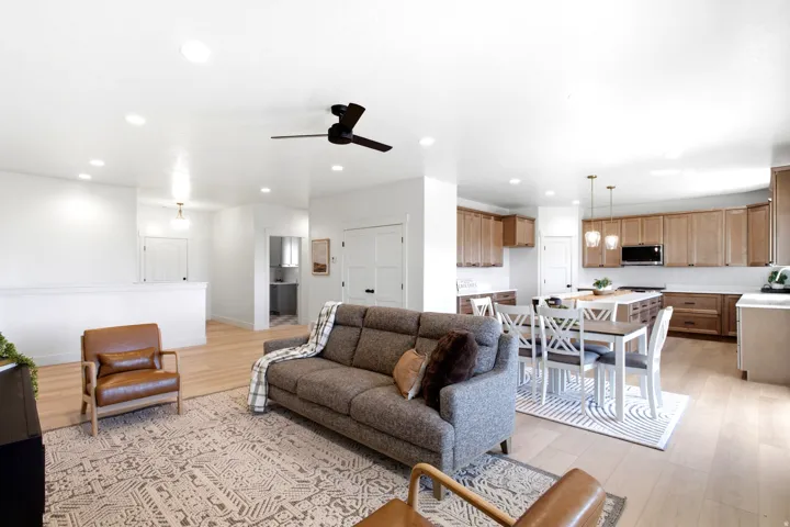 Open-concept living space with light wood-finish flooring, recessed lighting, and a dark-toned ceiling fan