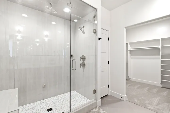 Glass-enclosed shower with pebble-finish flooring and a built-in bench