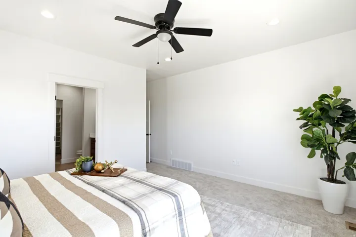 Recessed ceiling lighting, ceiling fan, white trim, light-colored carpeting, and a doorway leading to an adjoining room with built-in shelving