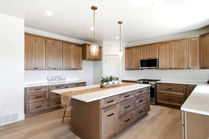 Kitchen featuring wood-finish cabinetry, white countertops, built-in stainless steel microwave, and wood-finish flooring