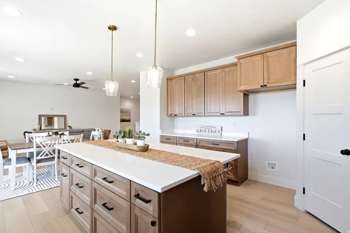 Kitchen island with white countertops, wood-finish cabinetry, and pendant lighting