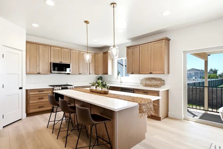 Kitchen featuring light wood-finish cabinetry, a large center island with counter seating, stainless steel appliances, recessed lighting, and wood-finish flooring