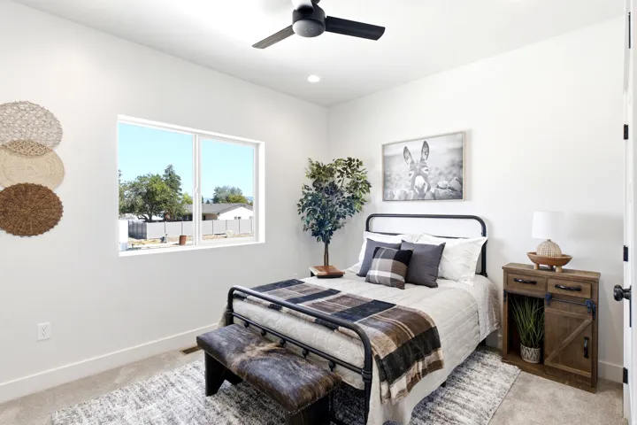 Recessed lighting, ceiling fan, white walls, built-in window, and a black metal bed frame