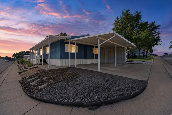 Blue exterior with white trim, covered carport, covered porch, and gravel landscaping