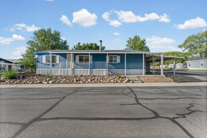 Blue siding exterior with white trim, covered front porch with white railing, and an attached carport