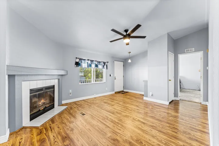 Wood-finish flooring, built-in fireplace with tile surround, ceiling fan, and recessed lighting