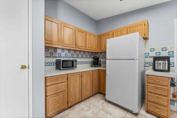 Kitchen featuring abundant wood cabinetry, patterned tile backsplash, and light-toned countertops