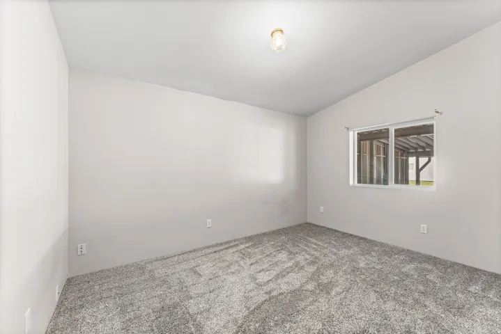 Spacious bedroom with neutral wall finishes, carpet flooring, and abundant natural light from a large window