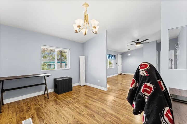 Vaulted ceiling, wood-finish flooring, chandelier lighting, window with horizontal blinds, ceiling fan