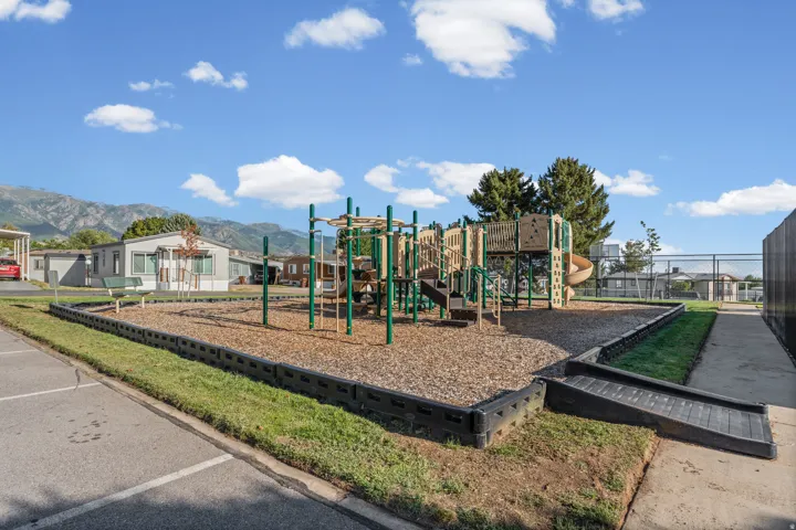 Playground area featuring a composite structure, wood chip ground cover, and a paved walkway