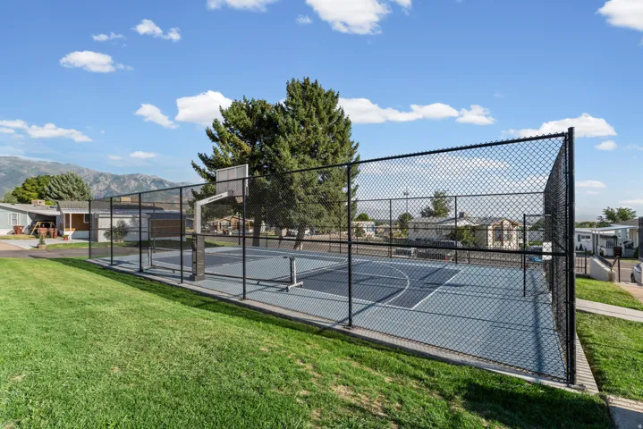 Fenced recreational court with a basketball hoop and painted lines