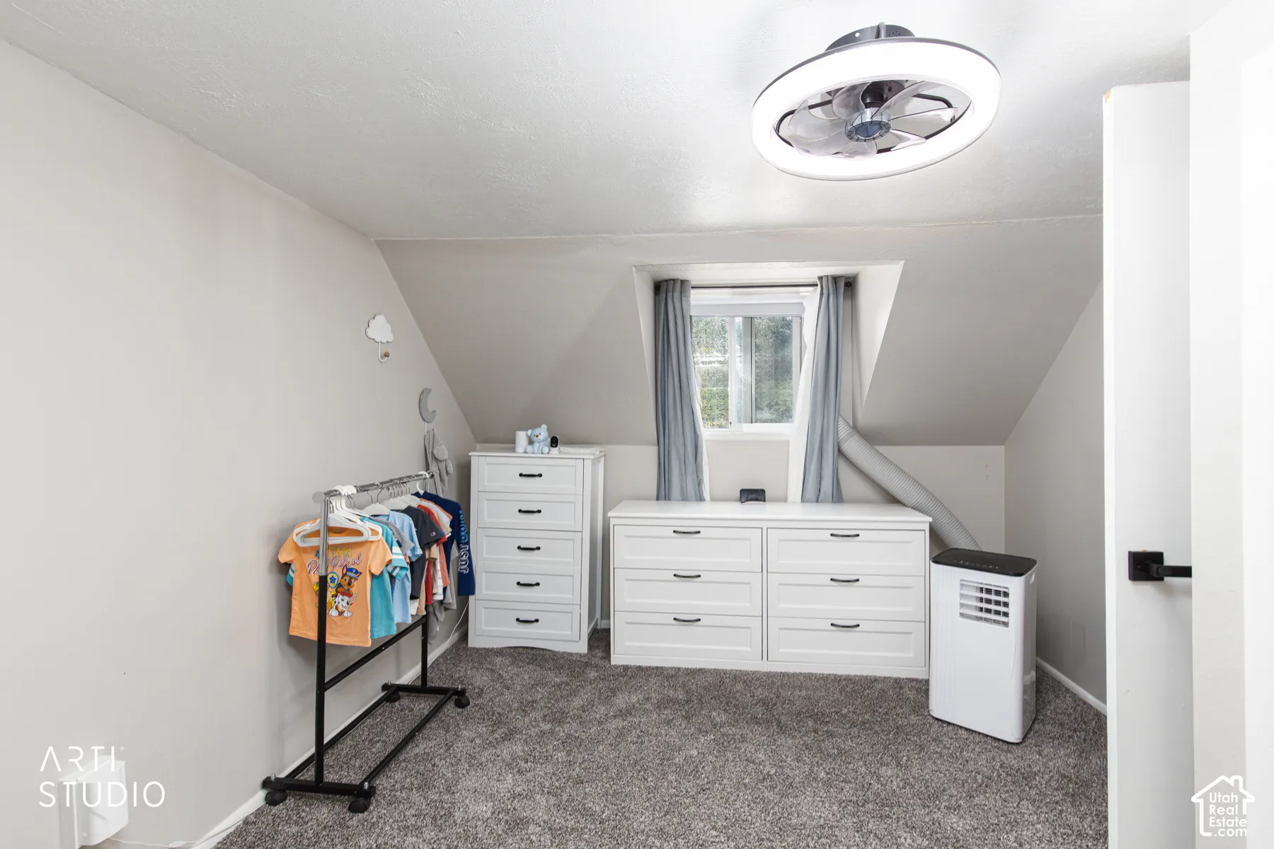 Recessed window with gray drapery, sloped ceiling, and textured carpet flooring