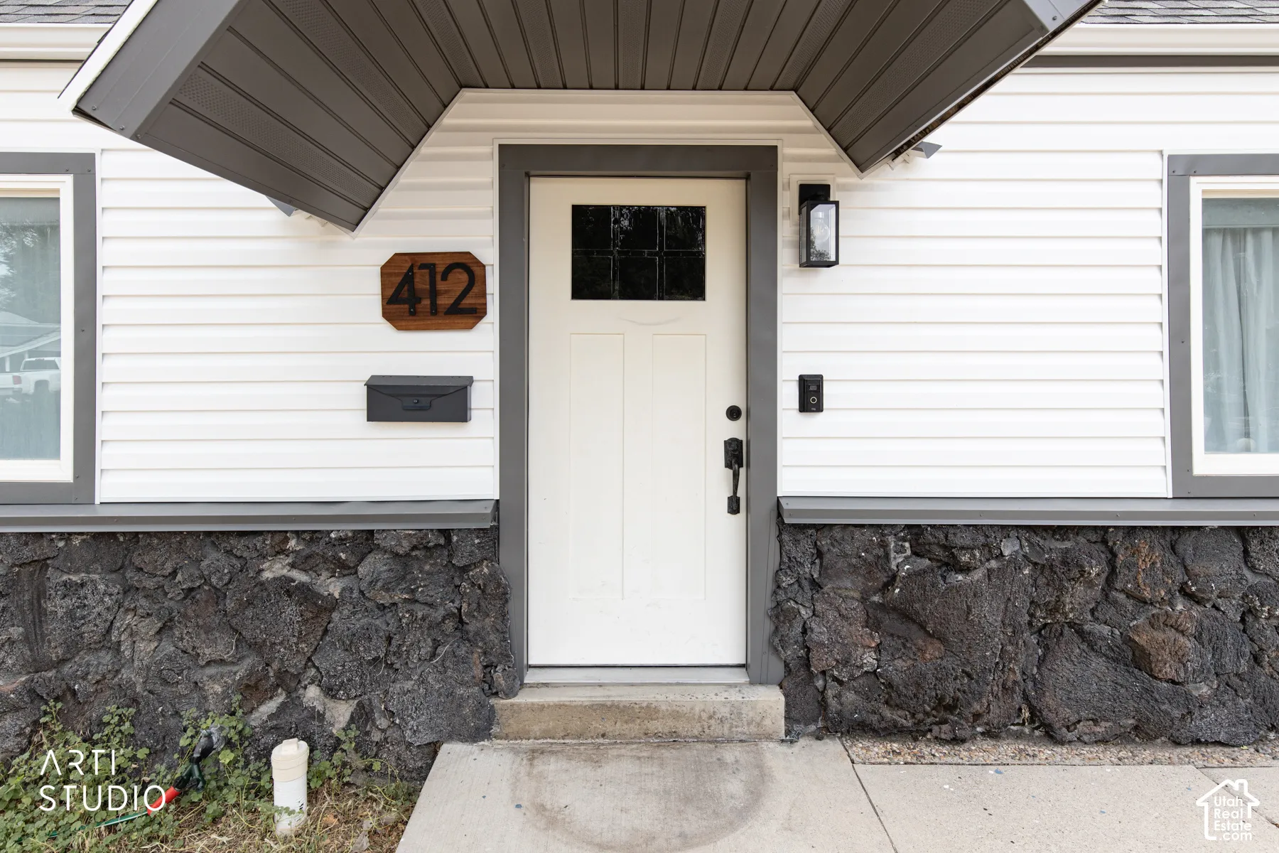 White siding exterior with a dark stone foundation