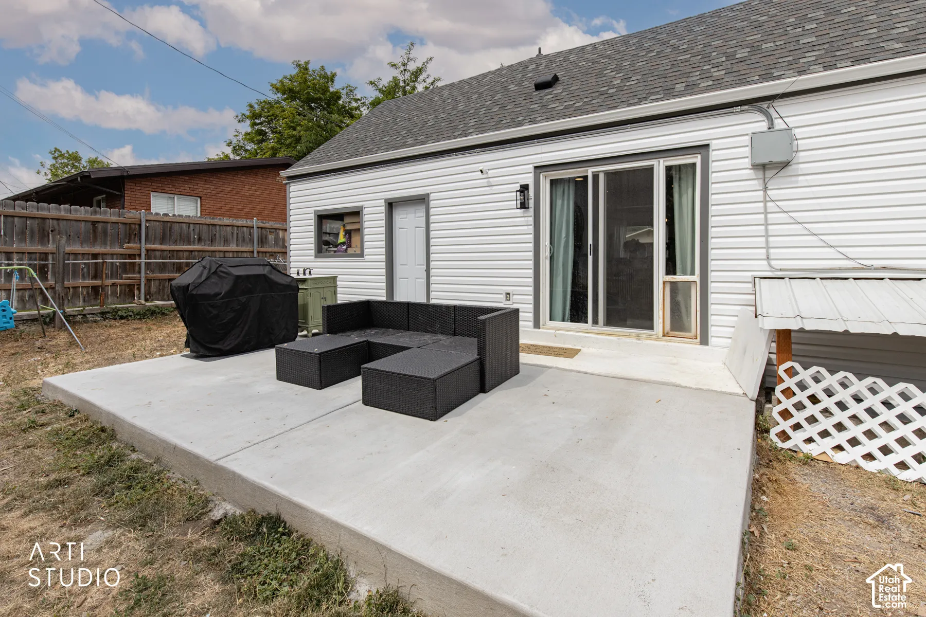 Concrete patio with a sliding glass door and white vinyl siding