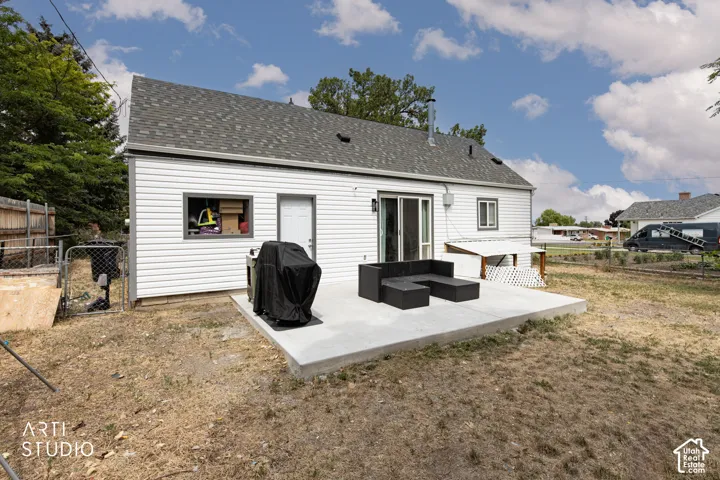 Outdoor concrete patio with sliding glass door access, white siding exterior, and a shingle roof