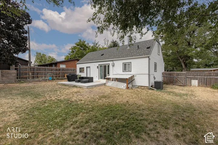 Expansive rear yard with a concrete patio, sliding glass door access, and a wood privacy fence