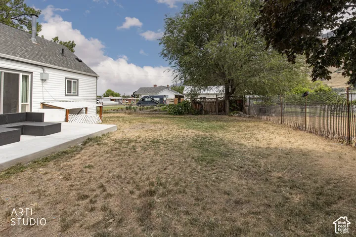 Expansive yard with mature trees, a concrete patio, and white siding