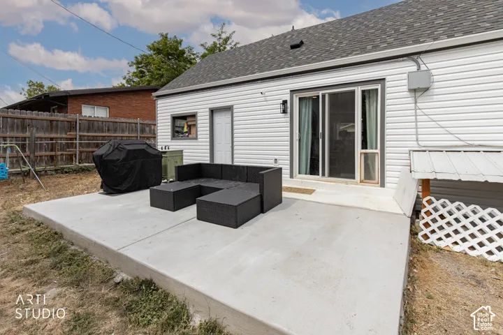 Concrete patio with a sliding glass door and white vinyl siding