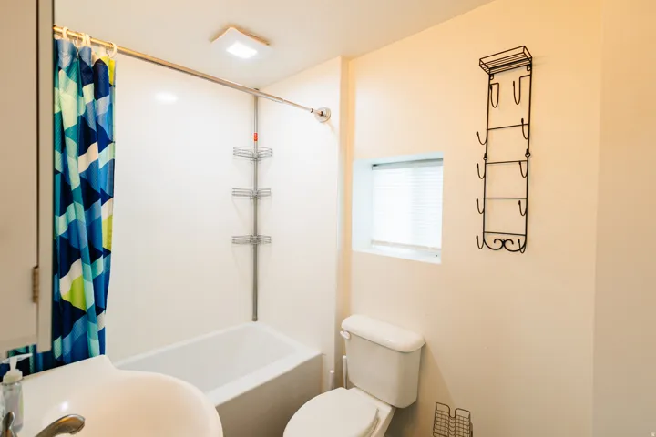 Bathroom featuring a white bathtub, toilet, and sink with a chrome faucet
