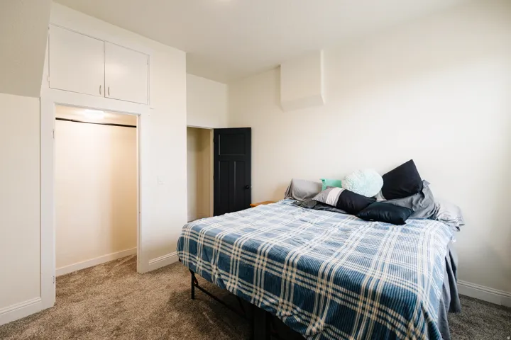 Plush carpeting, white walls, and a built-in overhead cabinet with storage