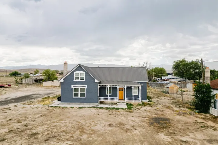 Charcoal gray exterior with white trim, metal roof, covered front porch, and a vibrant yellow front door