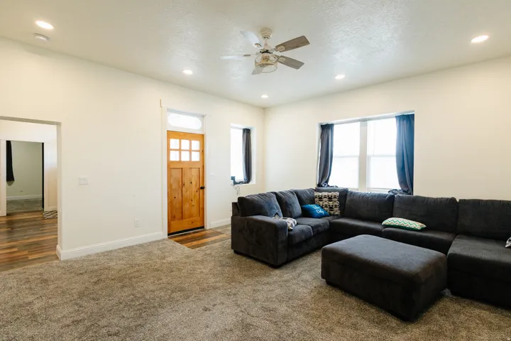Recessed lighting, ceiling fan, wood-panel entry door, and wood-finish flooring in adjacent area