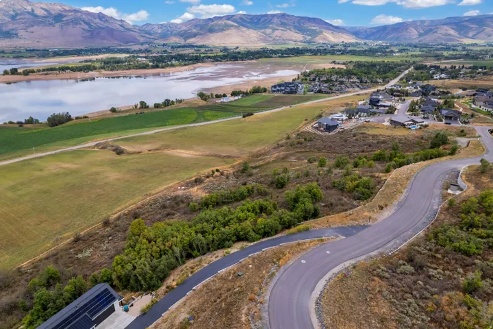 Mountain and lake scenery with a winding paved road and a distant residential area