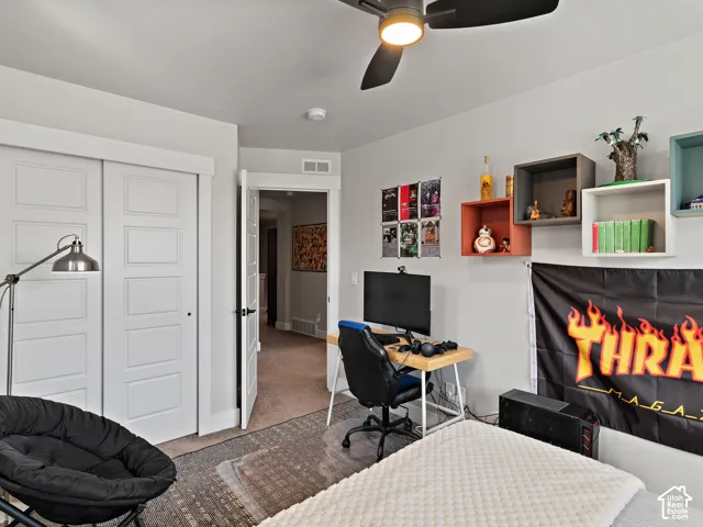 White two-panel sliding closet doors, ceiling fan with integrated lighting, wall-mounted shelving, and a desk area