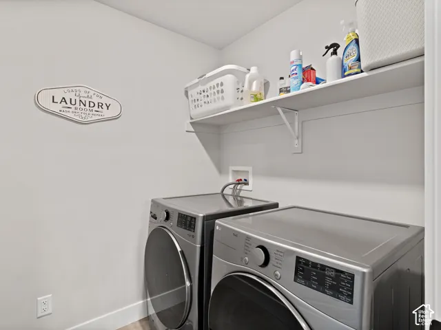 Dedicated laundry area featuring a wall-mounted shelf, light-toned walls, and wood-finish flooring