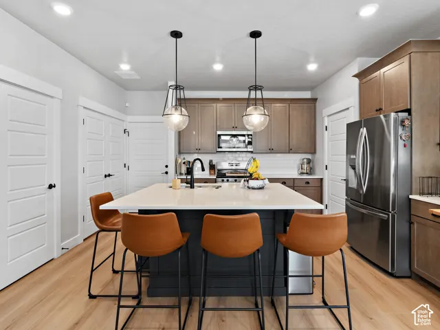 Kitchen featuring wood-finish flooring, a central island with countertop, and pendant lighting