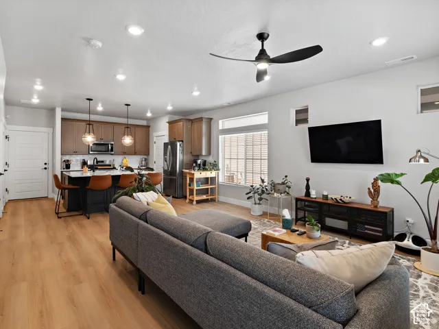 Open-concept living space with wood-finish flooring, recessed lighting, and a modern ceiling fan