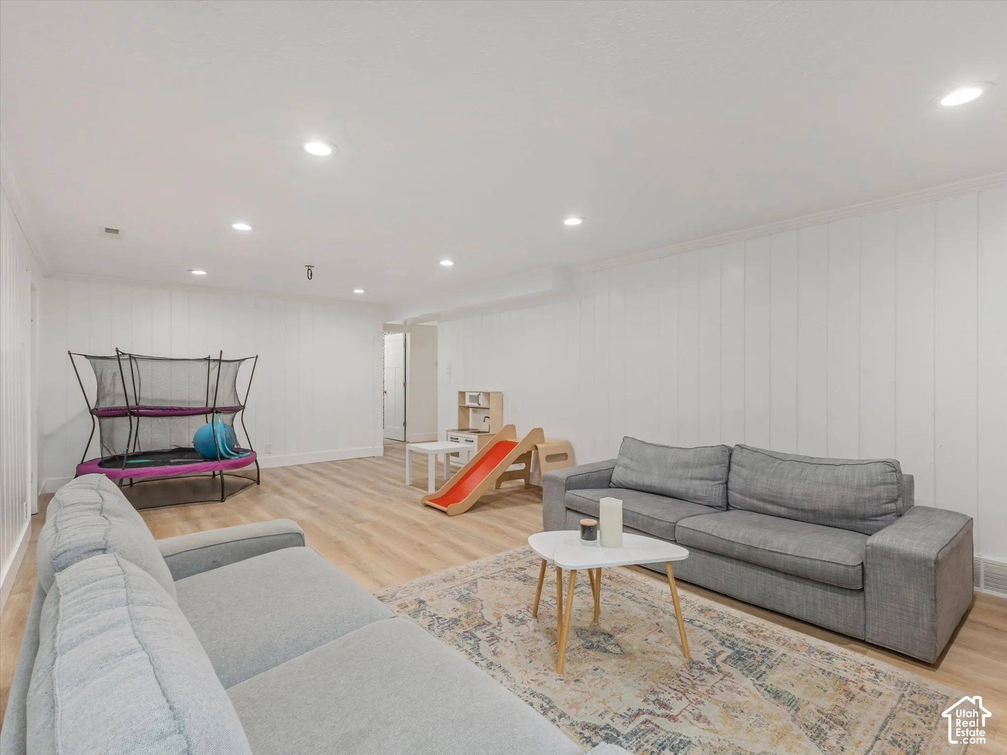 Recessed lighting, wood-finish flooring, white paneled walls, and crown molding throughout