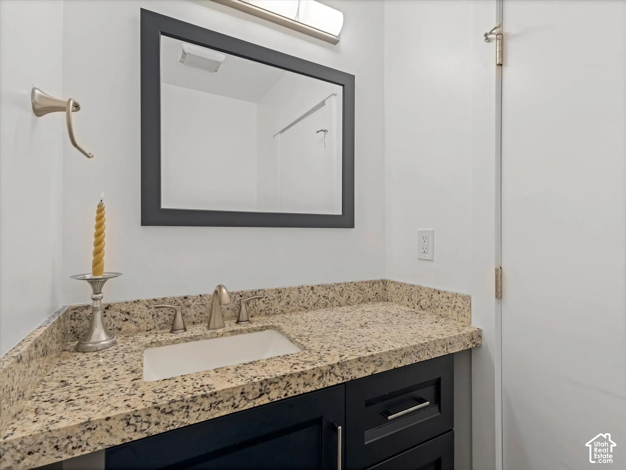 Bathroom vanity with granite countertop, integrated sink, brushed nickel faucet, and dark wood cabinetry