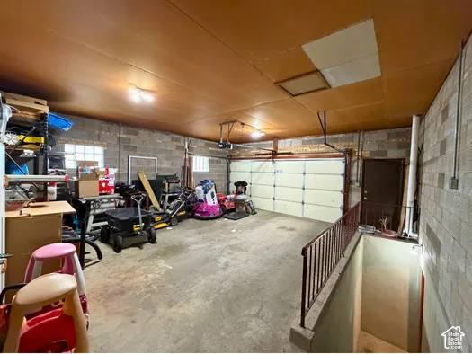 Concrete block walls with a wood-finish ceiling, featuring an overhead garage door and a side entry door